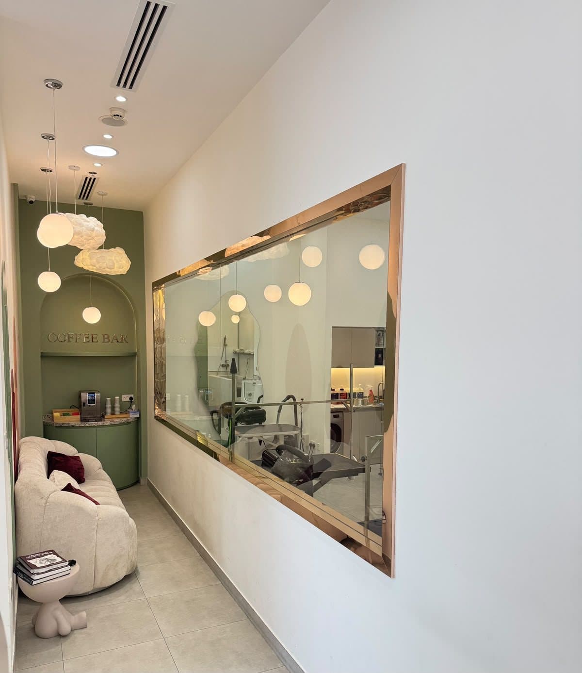 The sage coffee bar and cream sofa beside the grooming-room window