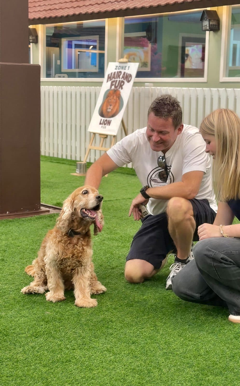A man kneeling to greet a cocker spaniel by a scent board