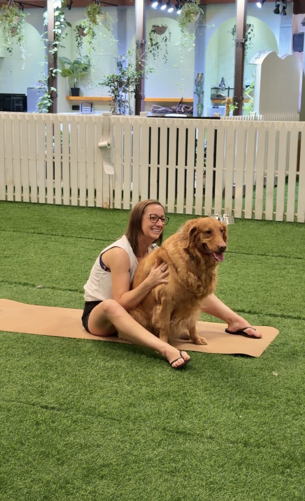 A woman sitting on a mat with her golden retriever