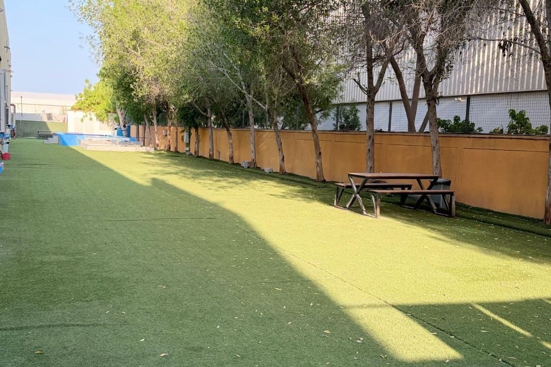 The long, tree-lined Flagship outdoor park with a picnic bench and the pool beyond